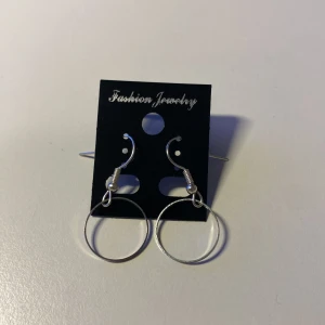Handgjorda Silverfärgade cirkelörhängen *Endast 1 Kvar* - Stilrena örhängen i silverfärg med enkel cirkelformad design. Hängande modell med krokfäste, perfekta för dig som gillar minimalistiska smycken. Passar till alla tillfällen och är lätta att matcha med andra accessoarer.