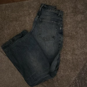 Blå wide jeans från Zara - Säljer ett par blåa jeans från Zara med bred passform och klassisk femficksdesign. Jeansen har en lätt tvättad look och ett litet hål på ena benet för en extra edge. Perfekta för dig som gillar en avslappnad och trendig stil.