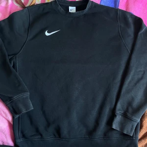 Svart Nike sweatshirt med logga - Svart sweatshirt från Nike. Tröjan är lite solblekt (därav priset). Men super skön, inga defekter. Strl L. Ordinarie pris 1149kr men säljer för 350kr, pris kan diskuteras vid snabb affär. 