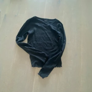 Svart långärmad tröja Gina Tricot - En svart långärmad tröja från Gina Tricot i ribbat material. Tröjan har en rund halsringning och smal passform, perfekt att styla med jeans eller kjol. Enkel och stilren design som funkar året runt.