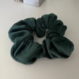 Mörkgrön scrunchie - Mörkgrön scrunchie i sammetsaktigt material. Endast använd ett fåtal gånger, säljer då den ej kommer till användning. 💚 Köp gärna bundle för att få rabatt!