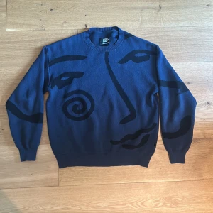 Blå stickad tröja från Sweet SKTBS - Säljer en blå stickad tröja från Sweet SKTBS i storlek XS. Tröjan har ett unikt konstnärligt ansiktsmotiv i svart på framsidan, rund hals och långa ärmar. Perfekt för dig som gillar streetstyle och vill sticka ut med en cool design.