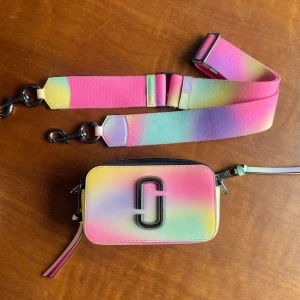 Rare Marc Jacobs ’THE snapshot’ - Säljer en sällsynt färg av den kända axelväskan ’The snapshot’ från modehuset Marc Jacobs. Färgen heter multicolor och är en blandning av vackra pastellfärger. Perfekt för sommar och festival! Väskan har bred, justerbar axelrem och dubbla dragkedjor. Snyggt svart logomärke framtill och detaljer i skinn. Helt i nyskick.