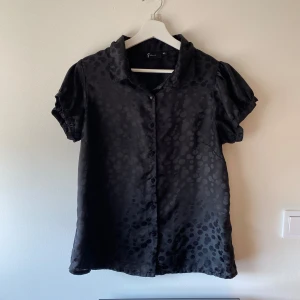 Satin blus  - Svart satin blus med knappar framtill. 