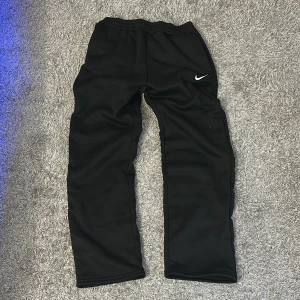 Svarta träningsbyxor från Nike - Säljer ett par svarta träningsbyxor från Nike med elastisk midja och det klassiska Nike-logotypen på benet. Byxorna har en avslappnad passform och är perfekta för sport och fritid.