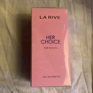 Her Choice Eau de Parfum från La Rive - Upptäck Her Choice Eau de Parfum från La Rive, en doft för kvinnor med en elegant och feminin touch. Förpackningen är i en mjuk rosa färg och innehåller 100 ml av denna franska doft. Perfekt för den som söker en sofistikerad och tidlös parfym.
