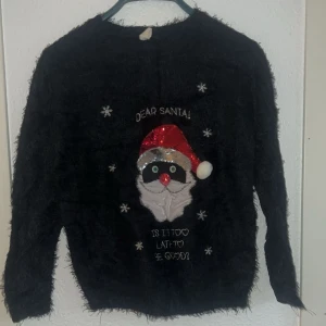 Svart jultröja från UNIQ YOUNG - Säljer en svart jultröja från UNIQ YOUNG med ett fluffigt material och ett roligt motiv av jultomten med texten 'Dear Santa! Is it too late to be good?'. Tröjan har långa ärmar och paljettdetaljer på tomtens luva. Perfekt för julens festligheter! 🎅✨sitter perfekt 👌🏽 