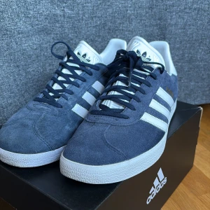 Add Ida’s Gazzelle Collegiate Navy / White / Gold Metallic - Säljer då jag ej använder skorna längre, inga defekter och sparsamt använda under vår/ tidig sommar förra året. Skorna är i storlek 43 1/3 men skorna är lite små i passformen vilket gör att de mer passar som storlek 42 . Slängde lådan efter jag hade köpt dem så den tillkommer ej och jag har tappat bort de vita extrasnörena. Pris kan diskuteras vid snabbt köp. Mvh, Leonard