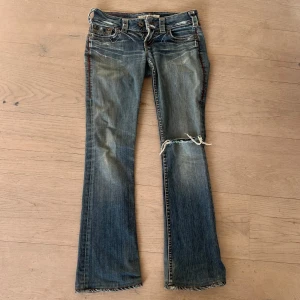 Blå jeans med slitningar - Snygga blå jeans från 1921 med slitningar och en trasig detalj på ena benet. De är bootcut och low waist!💕💕Midjemått:  39cm innerbenslängd: 76 cm (de har spruckit där bak som ni ser på sista bilden! men de är lagade!) Tar inga fler bilder