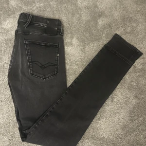 Svarta Replay jeans  - Snygga svarta jeans från Replay med en stilren design. De har en klassisk femficksmodell och en diskret logga på bakfickan. Perfekta för en stilren look. Jeansen är i slim modell och i så gott som nyskick. Nypriset: 1899kr säljer för endast 469kr. Storlek 33/34