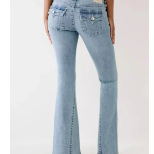 Ljusblå bootcut jeans - Snygga ljusblå jeans med bootcut-stil och dekorativa fickor bak. Perfekta för en avslappnad look med en touch av retro. De har en klassisk femficksdesign och en bekväm passform.