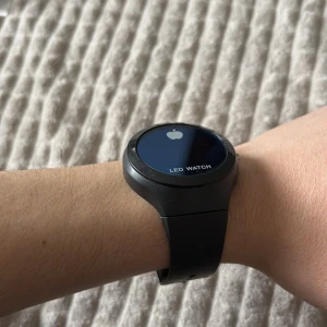 Svart LED-klocka med röd display - Snygg svart LED-klocka med en tydlig röd digital display. Klockan har en rund urtavla och ett justerbart armband. Perfekt för en modern och minimalistisk stil.