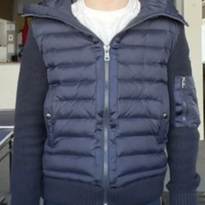 Moncler Cardigan - Säljer en snygg mörkblå( navy blue) jacka från Moncler. Jackan har en quiltad design med dragkedja och en praktisk huva. Den är långärmad och har ribbade detaljer på ärmar och nederkant. Perfekt för kyligare dagar!….Mitt pris 2500kr men kan sänkas vid snabb affär!…Helt fräsch och ren med inga fel!. Samt passar finns i storlek S och M