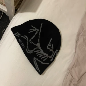 Svart mössa från Arc'teryx - Snygg svart mössa från Arc'teryx med ett grått mönster. Sjukt snygg och skön och typ aldrig använd, köpt för 599 på naturkompaniet 