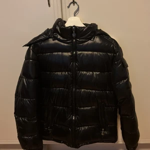 Svart pufferjacka med dragkedja - Snygg svart pufferjacka med dragkedja och praktiska fickor. Jackan har en hög krage och långa ärmar, perfekt för kyliga dagar. Den quiltade designen ger en modern look.