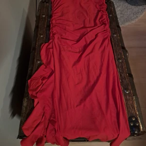 Röd kjol från Gina Tricot - Säljer en snygg röd kjol från Gina Tricot i storlek M. Kjolen har volangdetaljer och en rynkad design som ger en fin passform. Perfekt för att liva upp garderoben med en färgklick!
