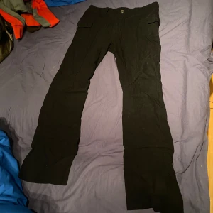 Kostym byxor - Säljer ett par svarta kostymbyxor med fickor framtill. Byxorna har en rak passform och är perfekta för en avslappnad stil. De har en knapp och dragkedja i midjan.