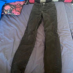 Svarta jeansbyxor - Snygga svarta jeansbyxor med hög midja och klassisk femficksdesign. Perfekta för en stilren look. De har en knapp och dragkedja framtill. Skinny jeans ifrån Gina, använda ett år väldigt fina fortfarande. Storlek xs.