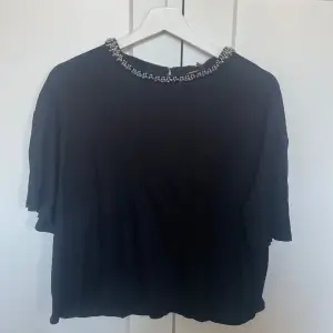Säljer en svart topp från H&M med pärldetaljer runt halsringningen. Toppen har korta ärmar och är i stolek 38.