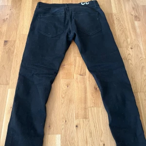 Svarta skinny jeans från Dondup - Säljer ett par svarta skinny jeans från Dondup. De har en modern passform och är perfekta för en stilren look. Byxorna har klassiska fem fickor och en bekväm midwaist. Perfekta för dig som gillar en tight passform.
