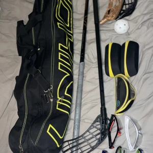 Svart innebandy väska från unihoc med klubbor och tillbehör - Säljer en svart innebandyväska från Unihoc. jag säljer också 2 klubbor den hel svarta är nästan aldrig använd eftersom den var min reserv klubba, på den andra klubban har jag nyss bytt Linda så den har bra kräpp sedan har jag också bytt blad så det skulle bli snyggare och det orange/ becha bladet som kommer med har en liten spricka. Sedan kommer ett annat svart blad som är hyfsat använt. Som tillbehör kommer det med 5 bra par glasögon av bra kvalité och tre askar. Pris kan diskuteras👍😁