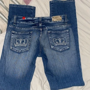 Blå jeans med kronor low waist - Snygga blå jeans från 5PM med unika broderade kronor på bakfickorna. Jeansen har en klassisk femficksdesign och en cool tvättad look, low waist. Dom här är från min mamma som är flera år gamla, runt 90talet. Storleken är mindre än XL Skriv privat för mer information 