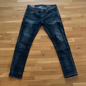 Mörkblå Dondup George - Säljer ett par unika mörkblåa dondup jeans med slitningar. Passar dig som är mellan 180 och 185cm.