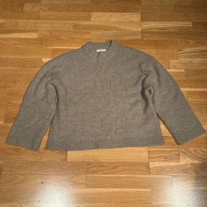 Beige stickad tröja från Gina Tricot - Säljer en mysig beige stickad tröja från Gina Tricot. Tröjan har en klassisk design med ribbade muddar vid ärmslut och nederkant. Perfekt för kyligare dagar.