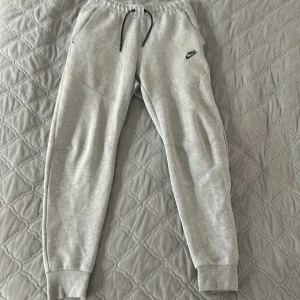 Nike Tech Byxor - Tja säljer nu dessa gråa Nike tech byxorna i storlek xs. Dom är i jätte bra skick skulle säga 8,5/10 och är inte använda så mycket. För mer bilder eller funderingar är de bara att skriva. Pris går o diskutera!!