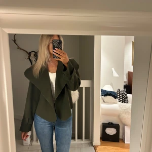 Olivgrön kavaj/jacka - Snygg olivgrön kavaj/jacka med en unik omlott-design och långa ärmar. Perfekt för en stilren look.