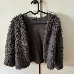 Mörkgrå fluffig pälskofta - En fluffig kofta från Gina