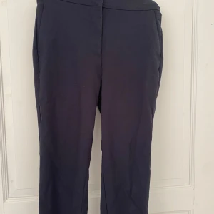 Mörkblå kostymbyxor - Snygga kostymbyxor från Zara med normal midja och rak passform. Byxorna har en bred linning och dekorativ detalj på utsidan av midjan. Perfekta för en clean och stilren look. Raka i benen