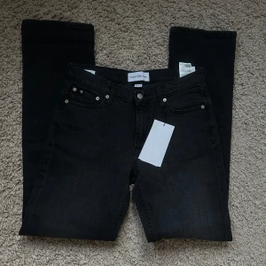 Svarta Lågmidjade jeans Calvin Klein - Snygga svarta jeans från Calvin Klein Jeans i modellen Low Rise Straight. Jeansen har låg midja, raka ben och klassisk femficksdesign. Tillverkade i mjukt denim med diskreta CK-detaljer.  Perfekta för en clean och stilren look.