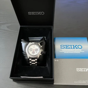 Seiko Prospex SSC911P1 kronograf - Säljer en Seiko Prospex SSC911P1 kronograf med solcellsteknik. Klockan har en silverfärgad länk i rostfritt stål, svart och vit urtavla med röda detaljer och tre subdials. Kommer i originalbox med extra länkbitar och manual. Perfekt för dig som gillar sportig och stilren design.