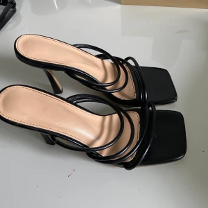 Classy svarta klackar - Säljer ett par stilrena svarta klackar med fyrkantig tå och smala remmar i minimalistisk design. Använda några få tillfällen men är i bra skick. 