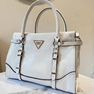Vit guess väska - Superfin Guess väska💞 En fläck inuti väskan finns, kolla sista bilden (syns inte när man använder den såklart)🙌🏻💞 Längd: 30cm, Höjd: 22cm