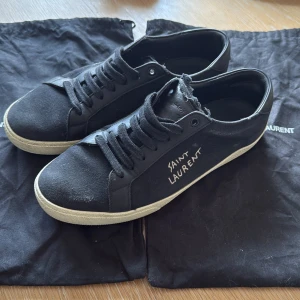 Svarta sneakers från Saint Laurent - Snygga svarta sneakers från Saint Laurent med vit sula och handskriven logga på sidan. Fint skick, minimalt med slitage på sula och häl. Storlek 42. Kan möjligtvis sänka pris vid snabb affär.