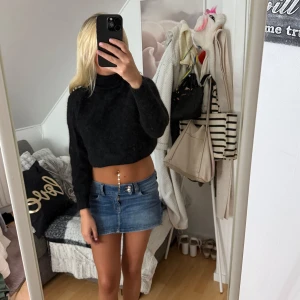 Svart croppad stickad tröja BikBok - Svart croppad stickad tröja från BikBok. Tröjan har polokrage och långa ärmar, perfekt för dig som gillar en trendig och mysig look. Passformen är loose och materialet är fluffigt och mjukt.