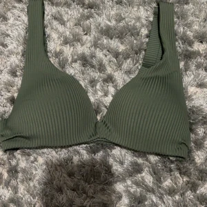 Grön pushup bikinitopp från H&M - Den är i strl 32 och har tre olika knäppningar i ryggen. Justerbara axelband