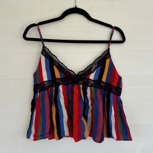 Randig linnetopp med spets från Zara - Färgglad linnetopp från Zara med vertikala ränder i blått, rött, orange, grönt, svart och vitt. Topp med tunna axelband, v-ringning och svarta spetsdetaljer längs bysten och under bysten. Perfekt för dig som gillar statement-plagg och lekfull stil. Aldrig använts med lappen kvar!🤩💕