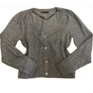 Grå kofta - Grå kofta från ONLY i storlek XS. Den har v-ringning, stängs med fyra knappar fram och långa ärmar med lite puff på axlarna som gör den lite extra fin. 