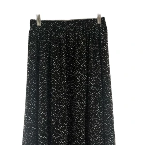 Svart långkjol med vita prickar - Svart långkjol med vita prickar och elastisk midja. Kjolen har ett flowy fall och är perfekt för dig som gillar en klassisk men ändå söt stil. Mönstret är småprickigt och tyget känns lätt och luftigt. Använd max 2 gånger. Skcikas snabbt!📦