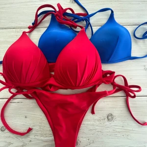 Röd och blå bikini med knyt - Två snygga bikinis i rött och blått med trekantsformade kupor och knyt i nacken och ryggen. Båda är i mjukt, stretchigt material som sitter skönt och ger en clean look. Perfekt för stranden eller poolen när du vill sticka ut med färg.