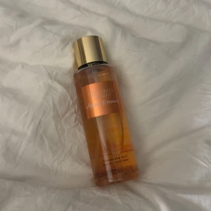 Victoria's Secret Amber Romance mist - Helt oanvänd Amber Romance från Victoria's Secret är en body mist i en genomskinlig orange plastflaska med guldig kork. Doften är varm och söt, perfekt för dig som gillar bäriga och vaniljiga toner. Flaskan rymmer 250 ml och har en snygg, modern design.