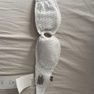 Vit broderad bikiniöverdel från H&M - Superfin vit bikiniöverdel från H&M med broderade detaljer och hålmönster. Bandeau-modell med avtagbara axelband och snygg ringdetalj i mitten. Perfekt för stranden eller poolen, riktigt fräsch och trendig look.