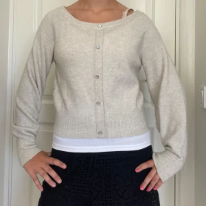 Beige kofta från H&M med pärlknappar - Superfin beige kofta från H&M med rund halsringning och dekorativa pärlknappar framtill. Tröjan är stickad, har långa ärmar och bred ribbad mudd vid ärmslut och nederkant. Perfekt att slänga över en topp för en chill och stilren look. Skriv om du undrar något, kolla min profil innan du trycker på köp nu 🩷🩷