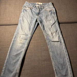 Levi's 511 Slim ljusblå jeans - Ljusblå Levi's 511. Jeansen har smal passform, normal midja och är tillverkade i mjukt denim med gul kontrastsöm. Jeansen är ganska skrynkliga och urtvättade så säljs för lågt pris.