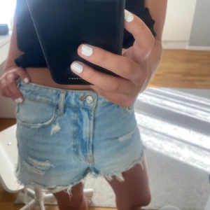 Ljusblå slitna jeansshorts - Säljer ett par ljusblå jeansshorts med snygga slitningar. 