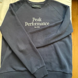 Mörkblå Peak Performance sweatshirt - Snygg mörkblå sweatshirt från Peak Performance med broderad logga på bröstet. Klassisk rund halsringning och långa ärmar med ribbade muddar. Använd men är i väldigt bra skick