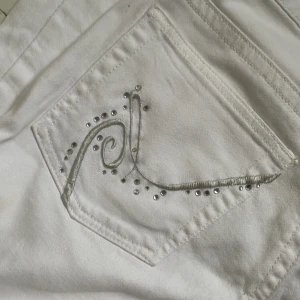Ikoniska låga Vita jeans med silverdetaljer - Snygga vita jeansbyxor från Lab med silverbroderi och små nitar på bakfickorna och låg midja. Klassisk femficksmodell med raka ben. Jätte 2000s icon as coola tyvärr passar de ej mej 🥲😘